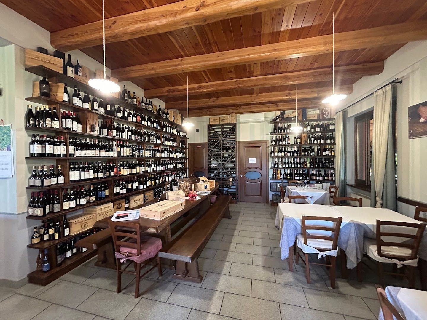 La sala dell'Osteria Bun Ben Bon con le pareti di bottiglie e i tavoli apparecchiati